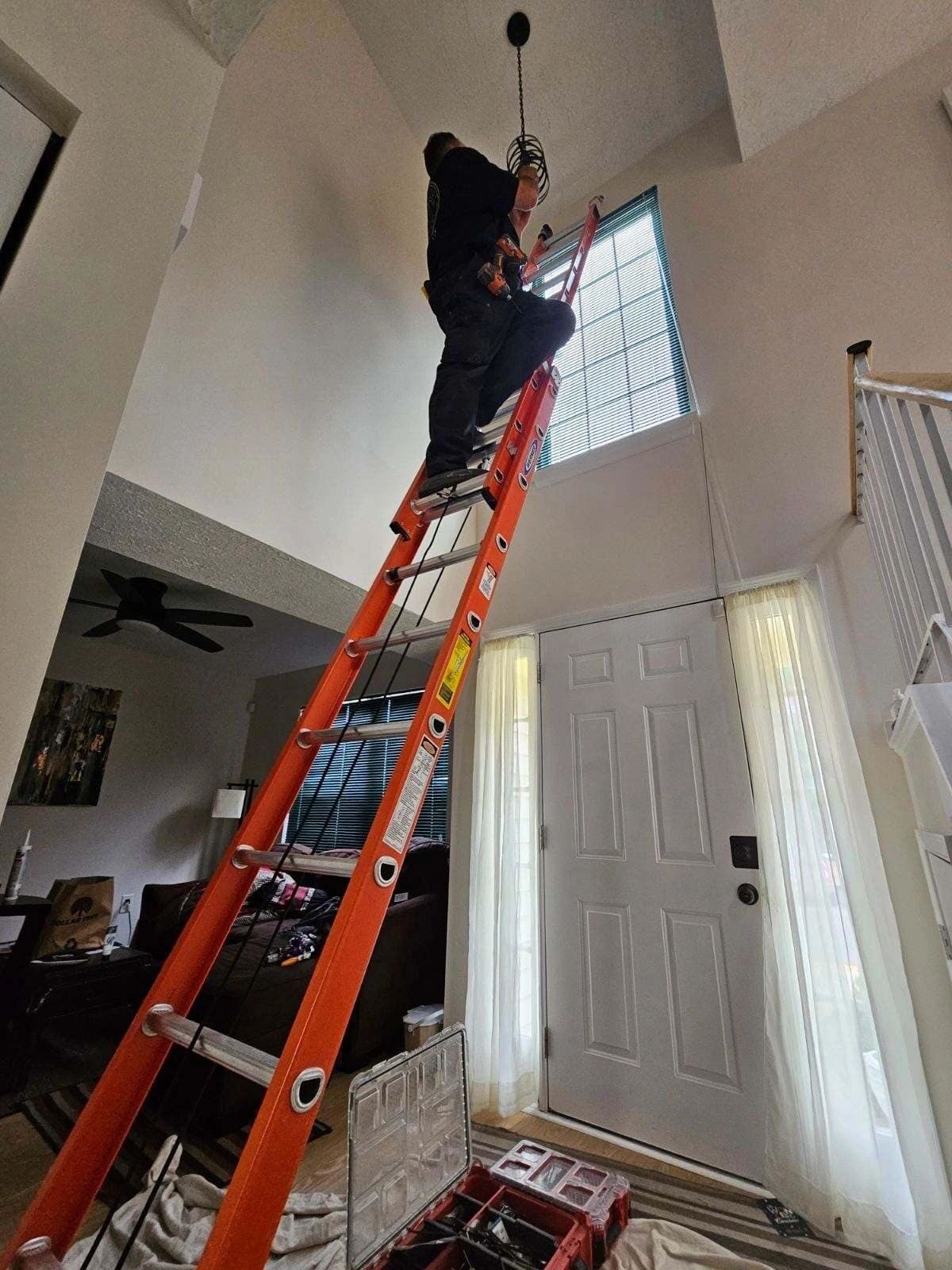 Mikk on a tall ladder installing a foyer light